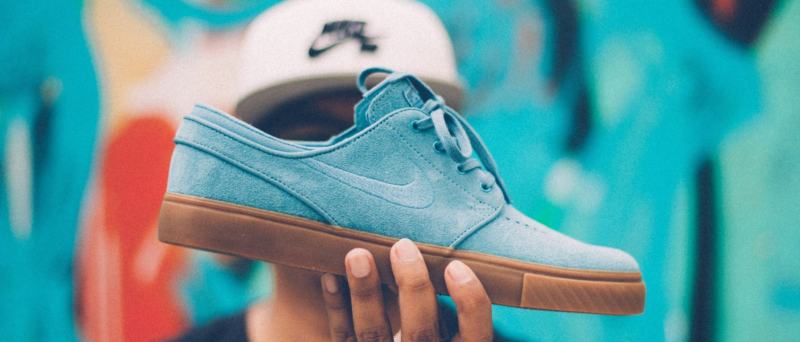 Blue sneaker with brown sole held by a person against a blurred background